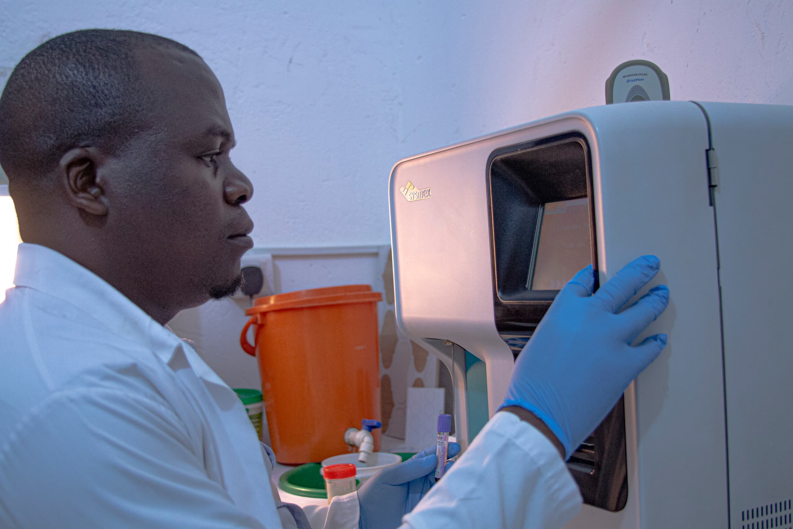 Technician in gloves operating the haematology analyser